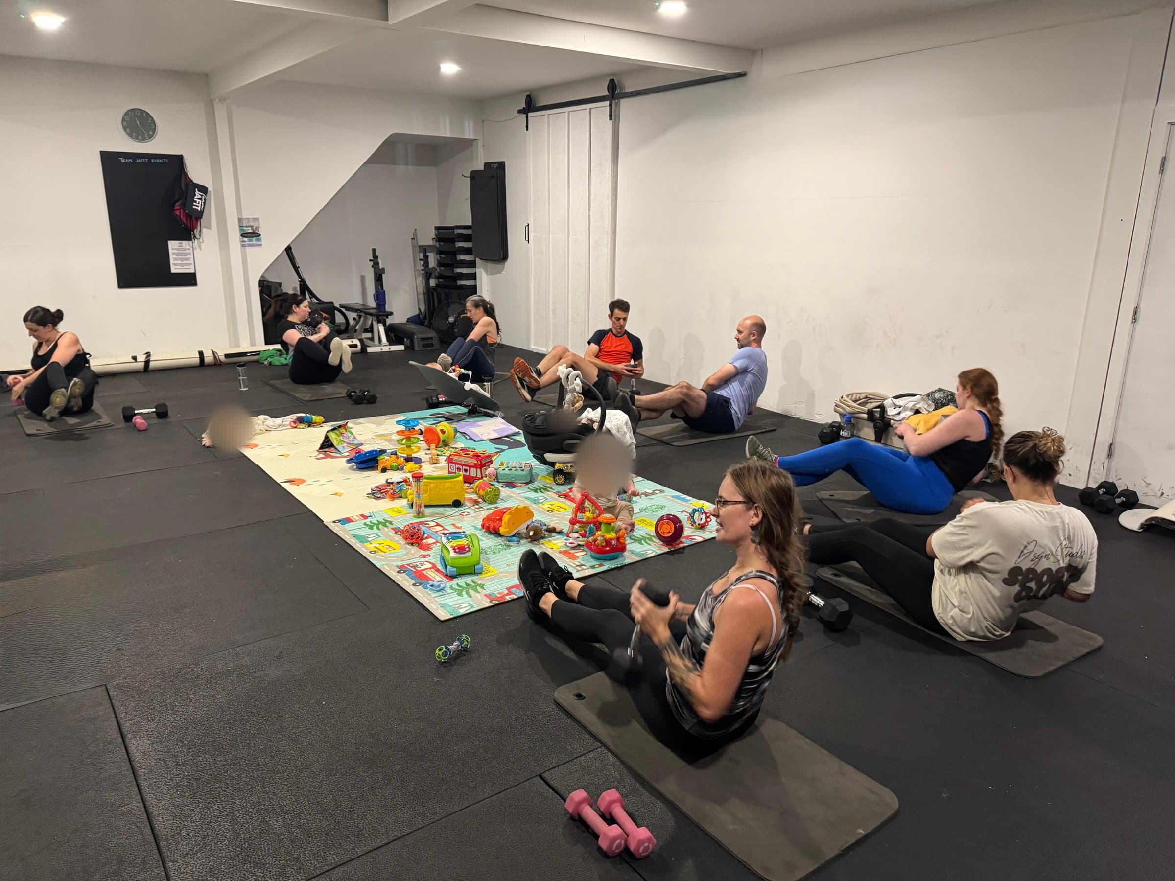 A parent and baby class at SD Martial Arts Studio in Colchester: mums and dads on mats around a play mat of toys, a baby sitting in the middle