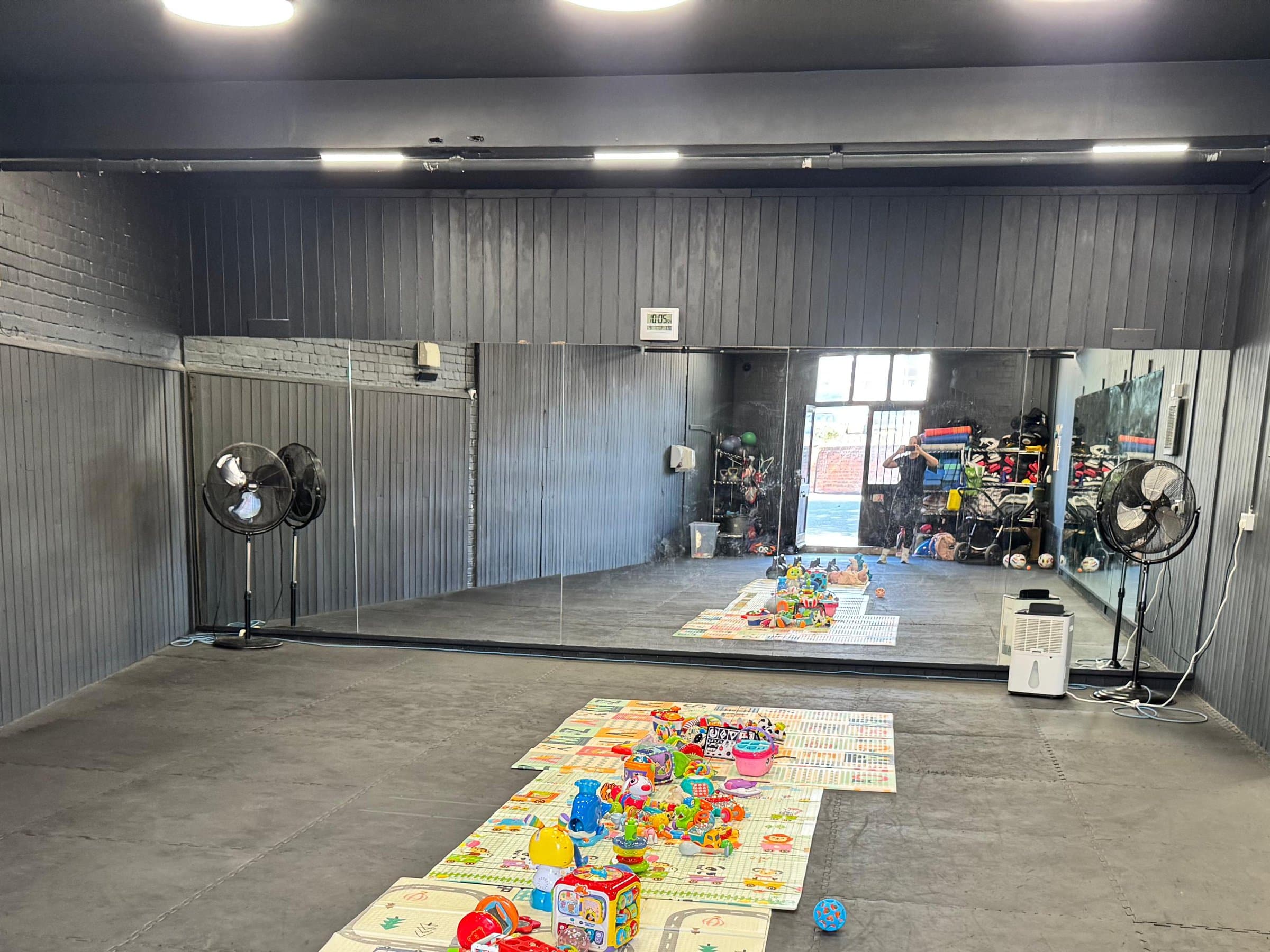 A play mat of toys in the middle of a mirrored studio, ready for class